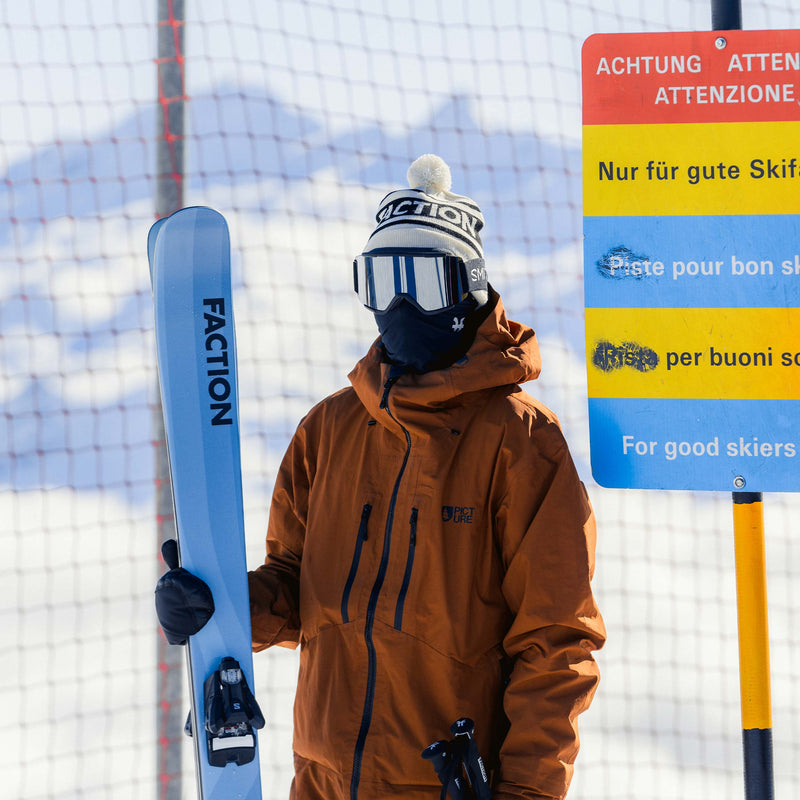 Skier holding blue Faction Dancer 2 all-mountain skis 2026