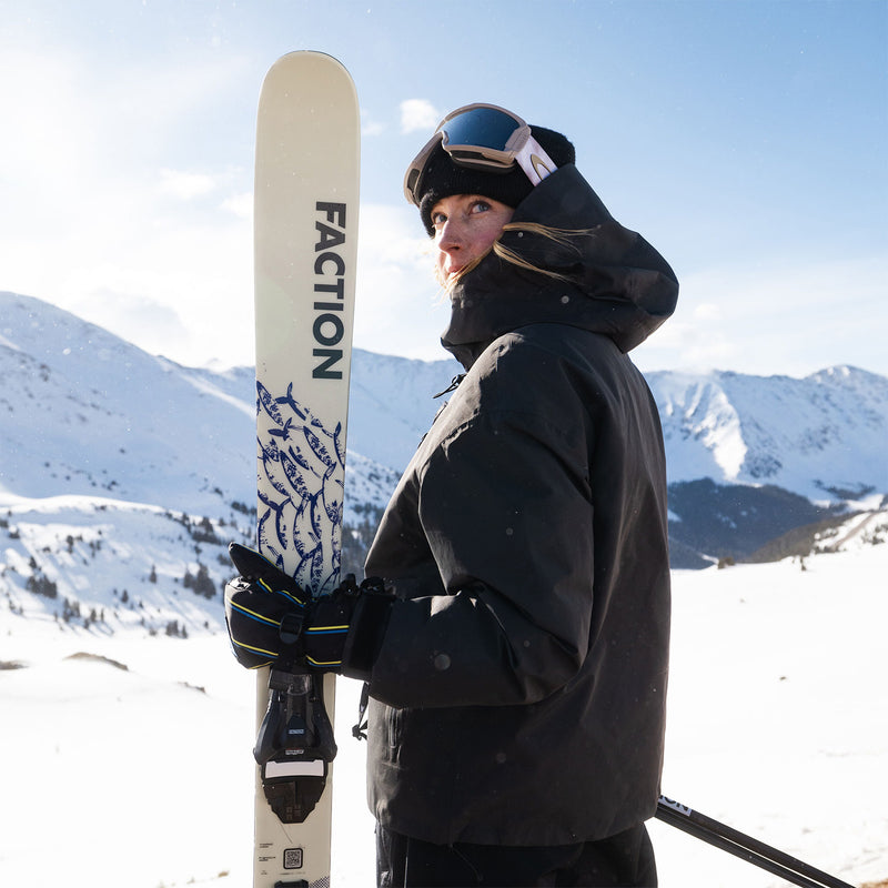 Women holding Faction Prodigy 1 Capsule white ski in a snowy alpine setting.