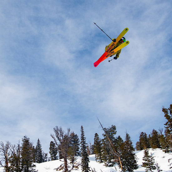Skier jumping over trees with Faction Prodigy 4 skis.