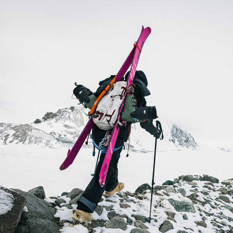 Person carrying Faction Agent 2 touring skis on a snowy mountain