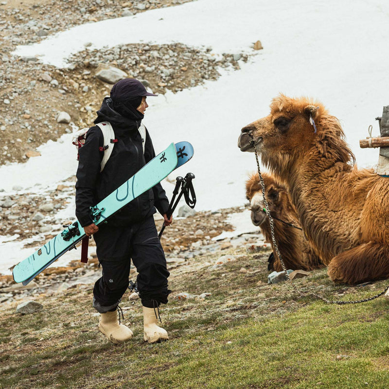 Person with Faction Agent 3 Skis standing next to a camel in a snowy landscape
