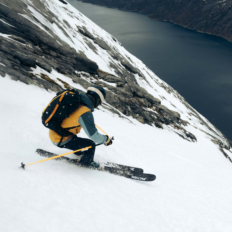 Person skiing down a snowy mountain with a lake in the background