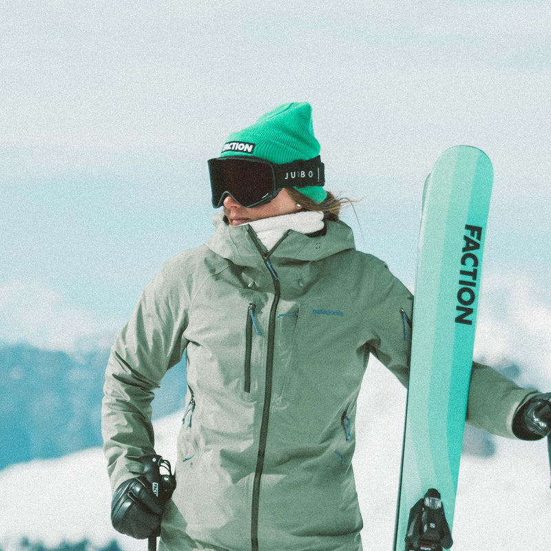 Skier wearing Faction skis logo beanie in green