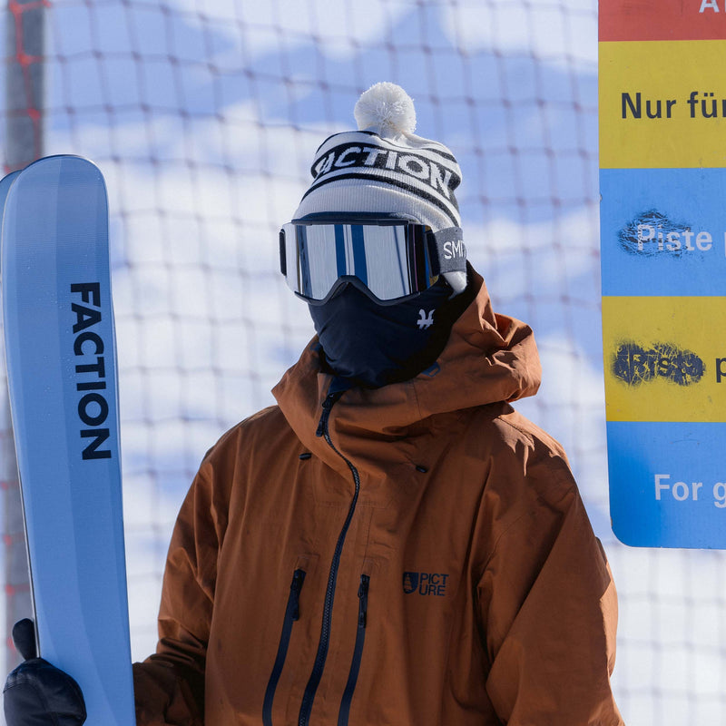 Skier wearing Faction skis pompom beanie in white