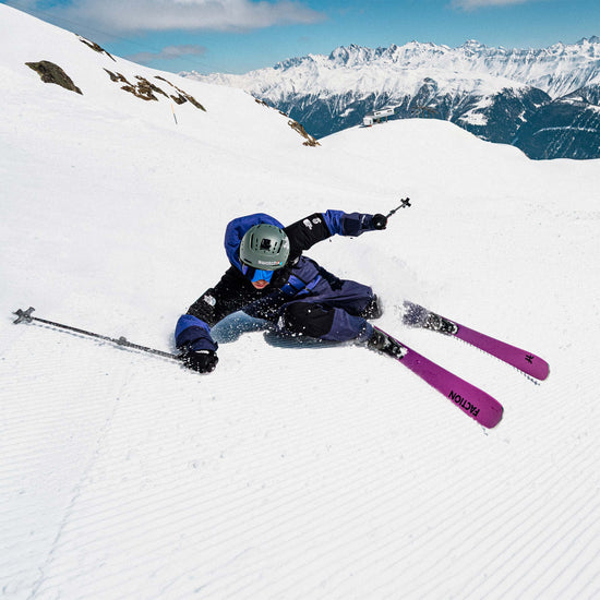 Skier carrying pink Faction Dancer 89 skis under a ski lift