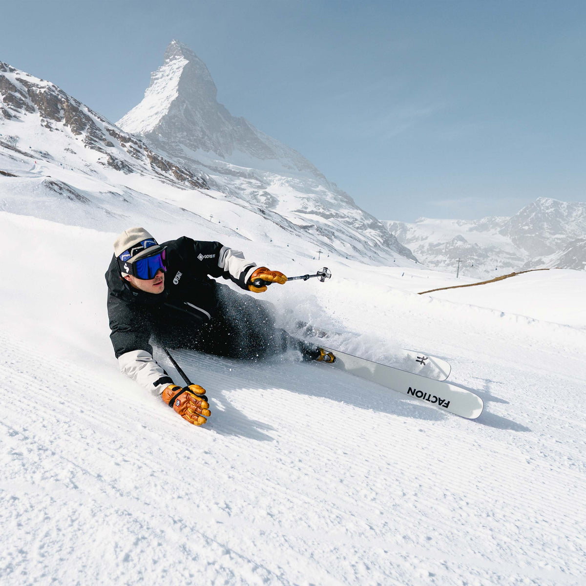 Skier carving on piste with the Faction Dancer 89 TI with a sunny mountain background