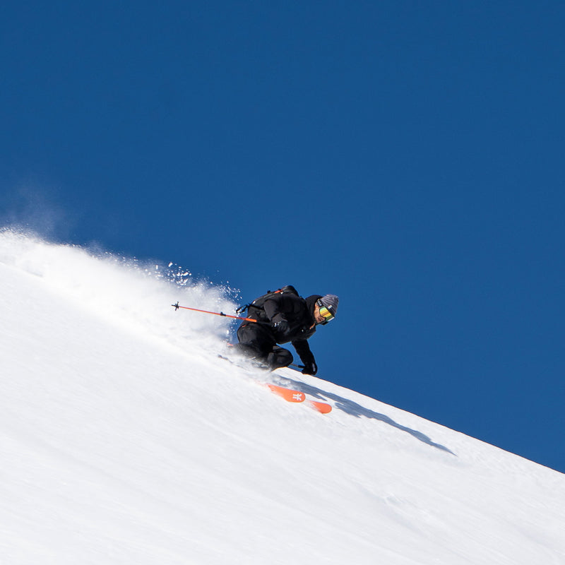 Skier in action on a snowy slope with a clear blue sky on Faction La Machine skis