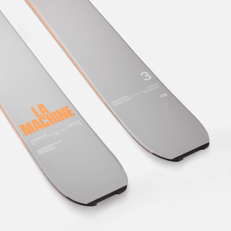 Two gray Faction skis with orange text on a white background