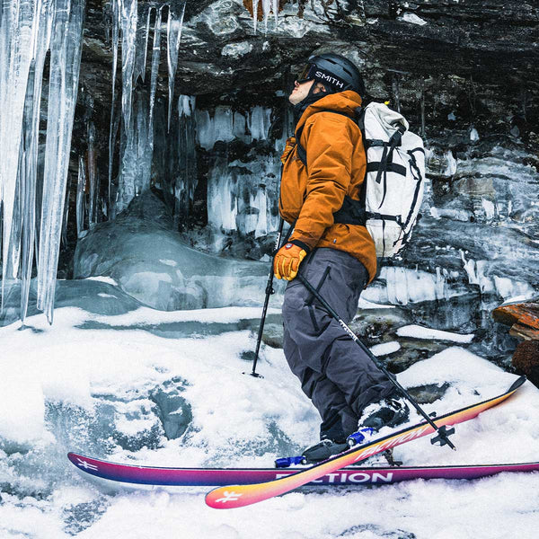 Person skiing in a snowy, icy cave with icicles hanging from the ceiling.