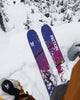 Two Faction skis in the snow with a person wearing gloves and a jacket.